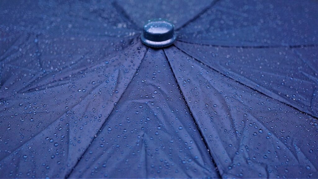 Close‑up of a tent’s waterproof rainfly being secured with stakes and guylines.