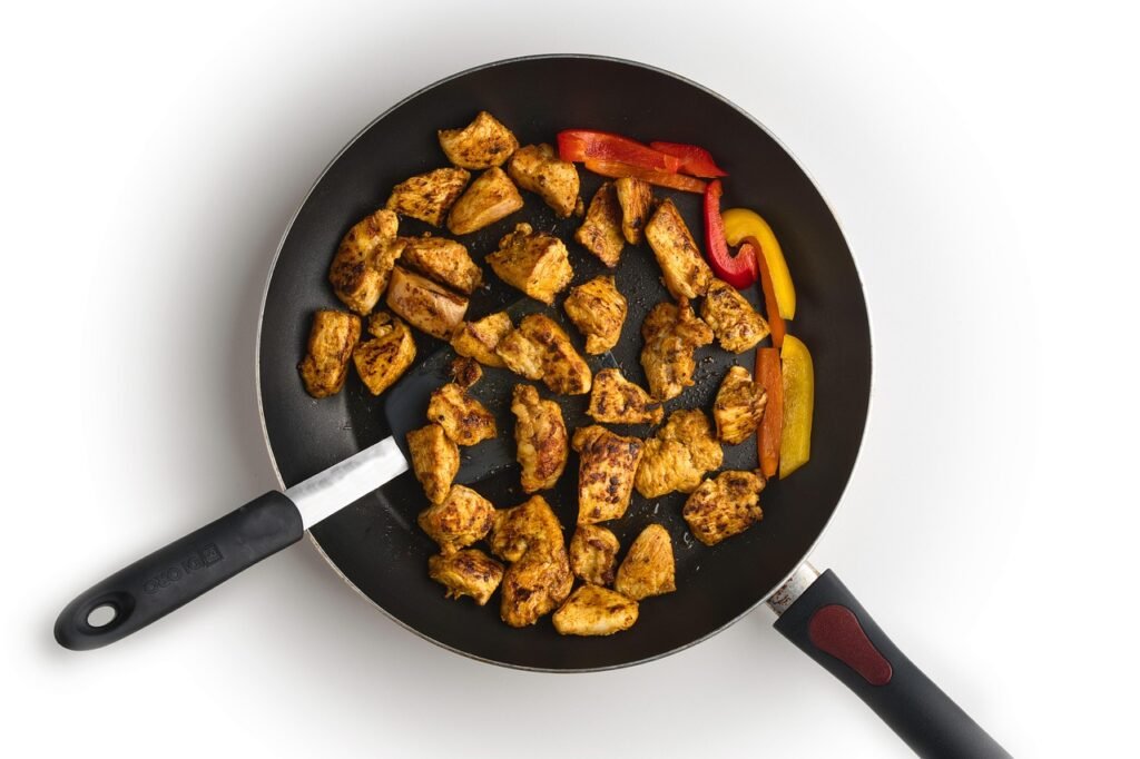 camper cooking dinner in an anodized aluminum pan at a campsite picnic table