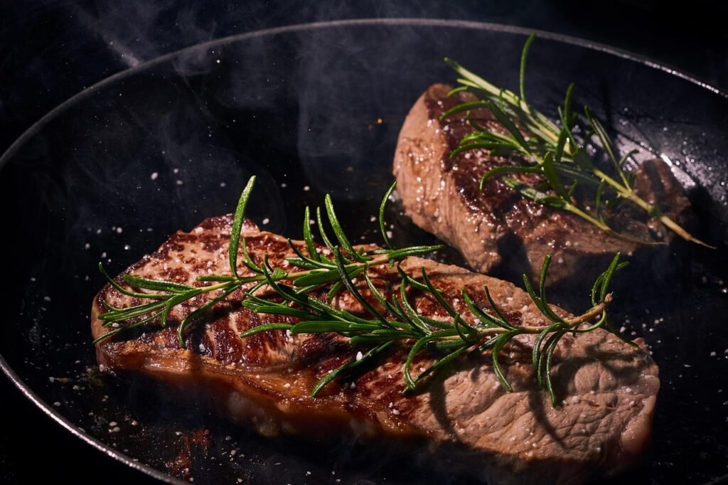 cast iron skillet with sizzling food sitting over a glowing campfire grill grate