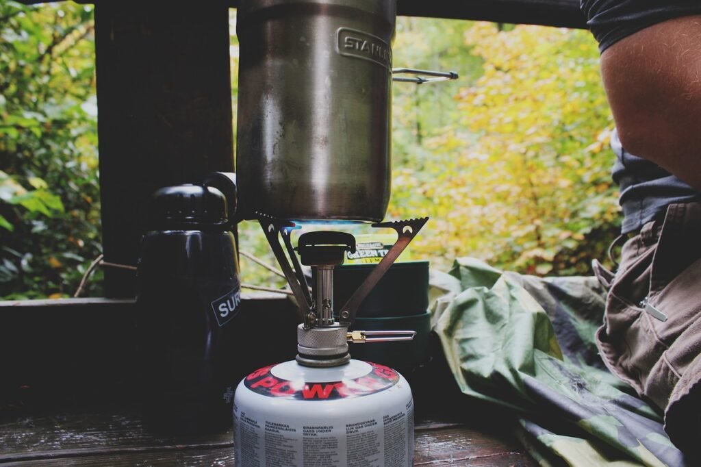 close up of camping cookware set resting on a portable camp stove in a pine forest